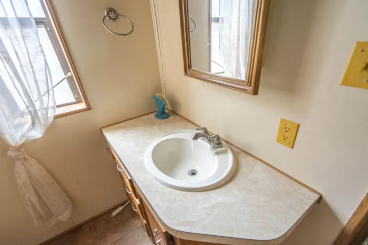 Built-in vanity with an integrated sink, laminate countertop, and wood-finish cabinetry