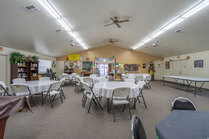 Spacious communal room featuring a vaulted ceiling with multiple ceiling fans and integrated fluorescent lighting