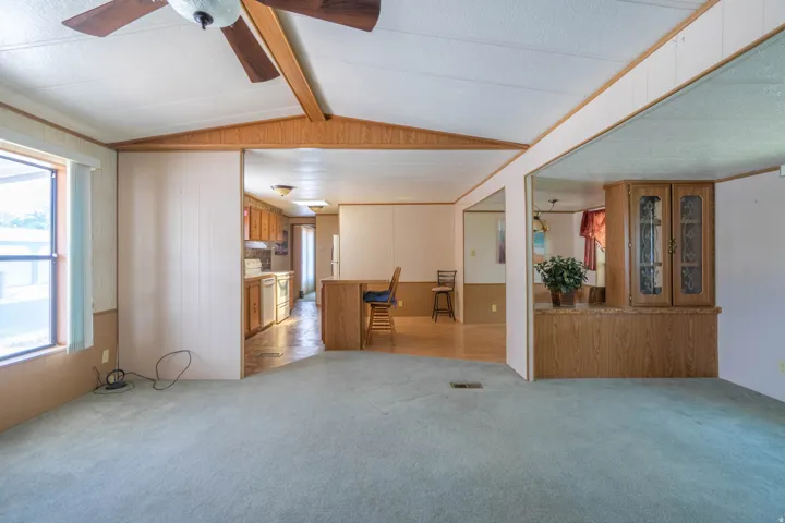 Interior with a vaulted ceiling, wood-finish beam, and a ceiling fan