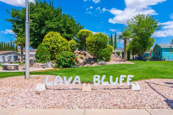 Landscaped entry featuring a gravel bed, mature trees, and a manicured lawn