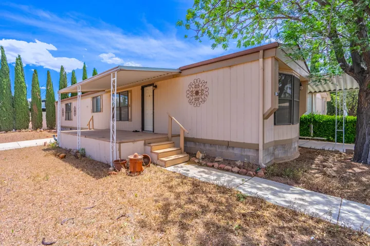 Front facade featuring a covered porch with a metal awning, wood steps, and a concrete pathway