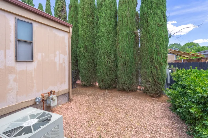 Exterior siding with a single window and brown trim, featuring a gravel ground cover