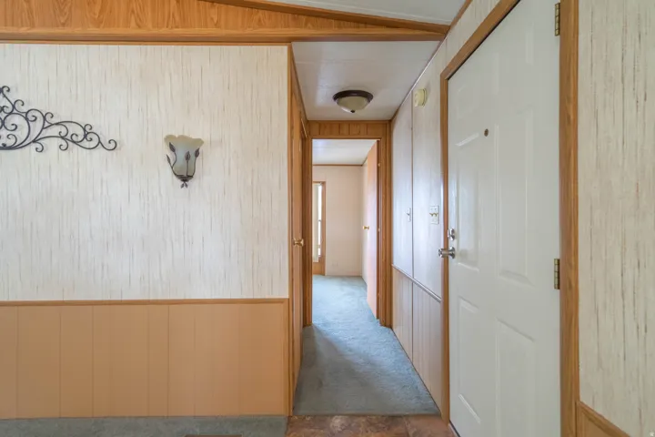 Entryway featuring a paneled door, wood-finish trim, and a wall sconce