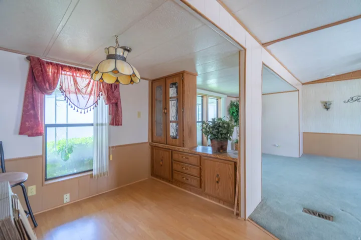 Dining area featuring wood-finish flooring, a built-in wood-finish hutch with glass-front cabinetry, and a decorative overhead light fixture