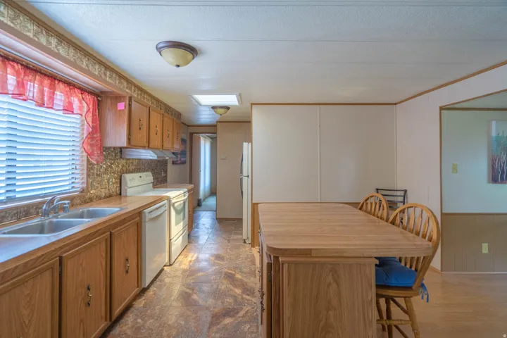 Kitchen featuring wood-finish cabinetry, a double basin stainless steel sink, and white appliances