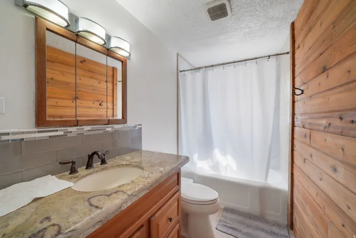 Bathroom featuring a wood-finish vanity with a stone countertop and an integrated sink