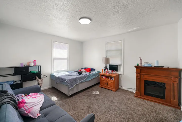 Carpeted room featuring a built-in fireplace, two windows, and a flush-mount ceiling light fixture