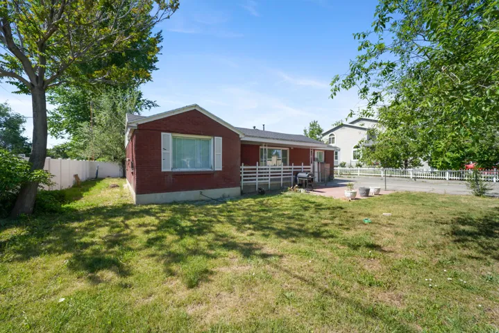 Expansive rear yard featuring green lawn, mature trees, and a brick exterior home