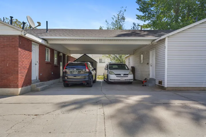 Concrete driveway featuring a covered carport, brick exterior, and siding exterior