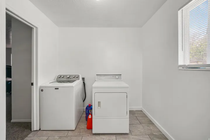Dedicated laundry space featuring neutral tile flooring and white walls