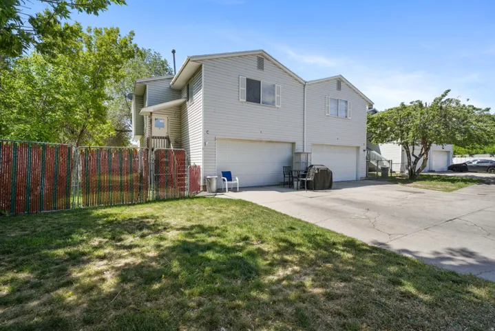 Exterior featuring two attached garages, light-colored siding, and a fenced yard area