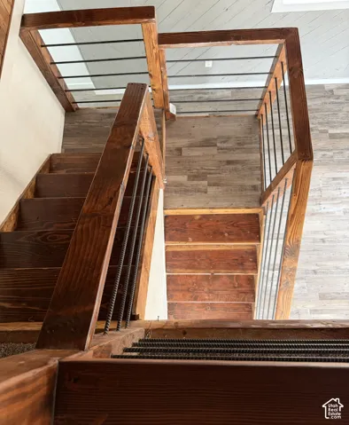 Wood staircase with dark stain, featuring horizontal metal balusters and wood-finish flooring