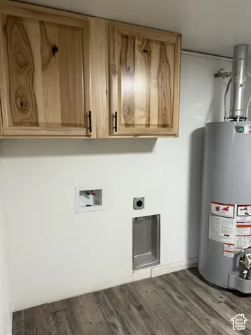 Utility space featuring wood-finish wall cabinetry with black pulls, a water heater, and wood-finish flooring