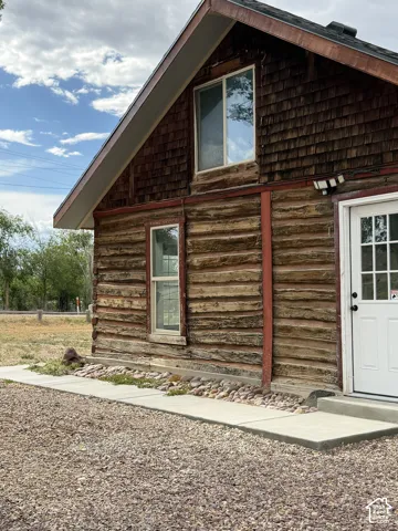 Rustic log siding and shingle accents with a white paneled entry door