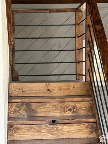 Staircase featuring rich wood treads and risers, complemented by a wood-framed railing with horizontal metal balusters