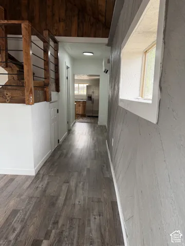 Wood-finish flooring throughout, featuring a wood accent ceiling and a wooden staircase with black metal balusters