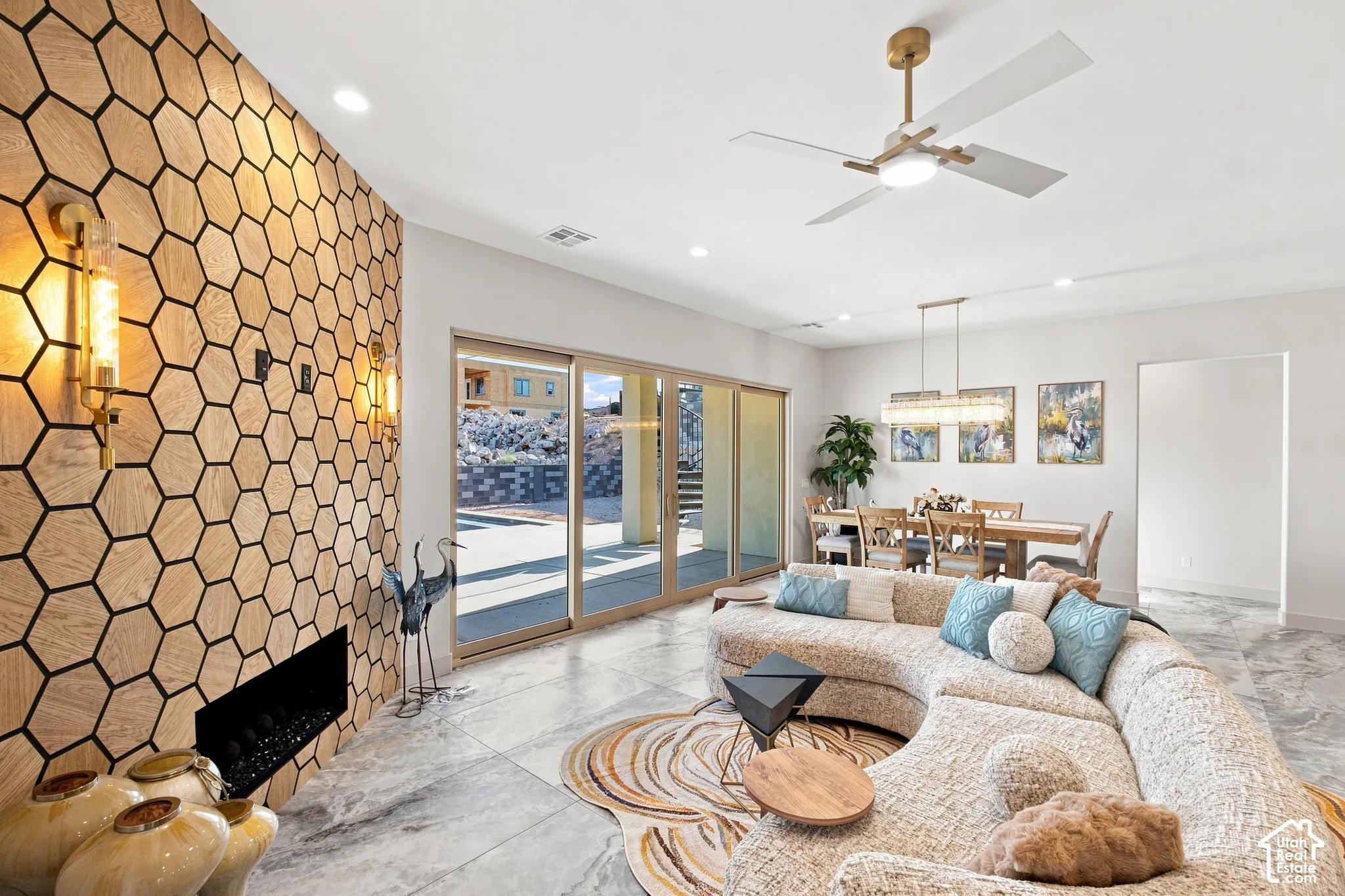 Hexagonal wood panel accent wall with embedded fireplace, recessed ceiling lighting, and a modern ceiling fan