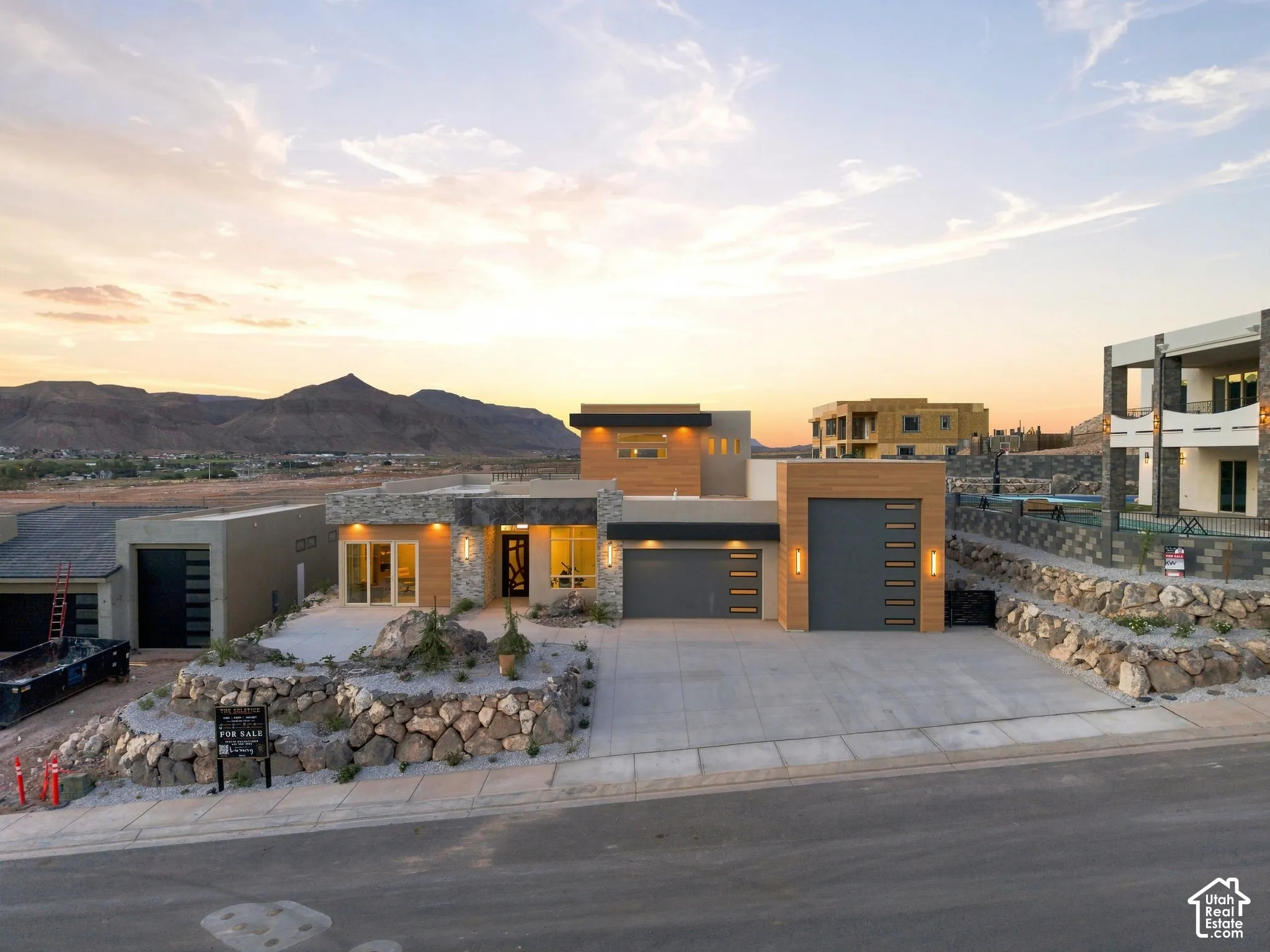 Modern exterior architecture featuring a multi-tone facade, integrated garage with a wood-finish door, and stone accents