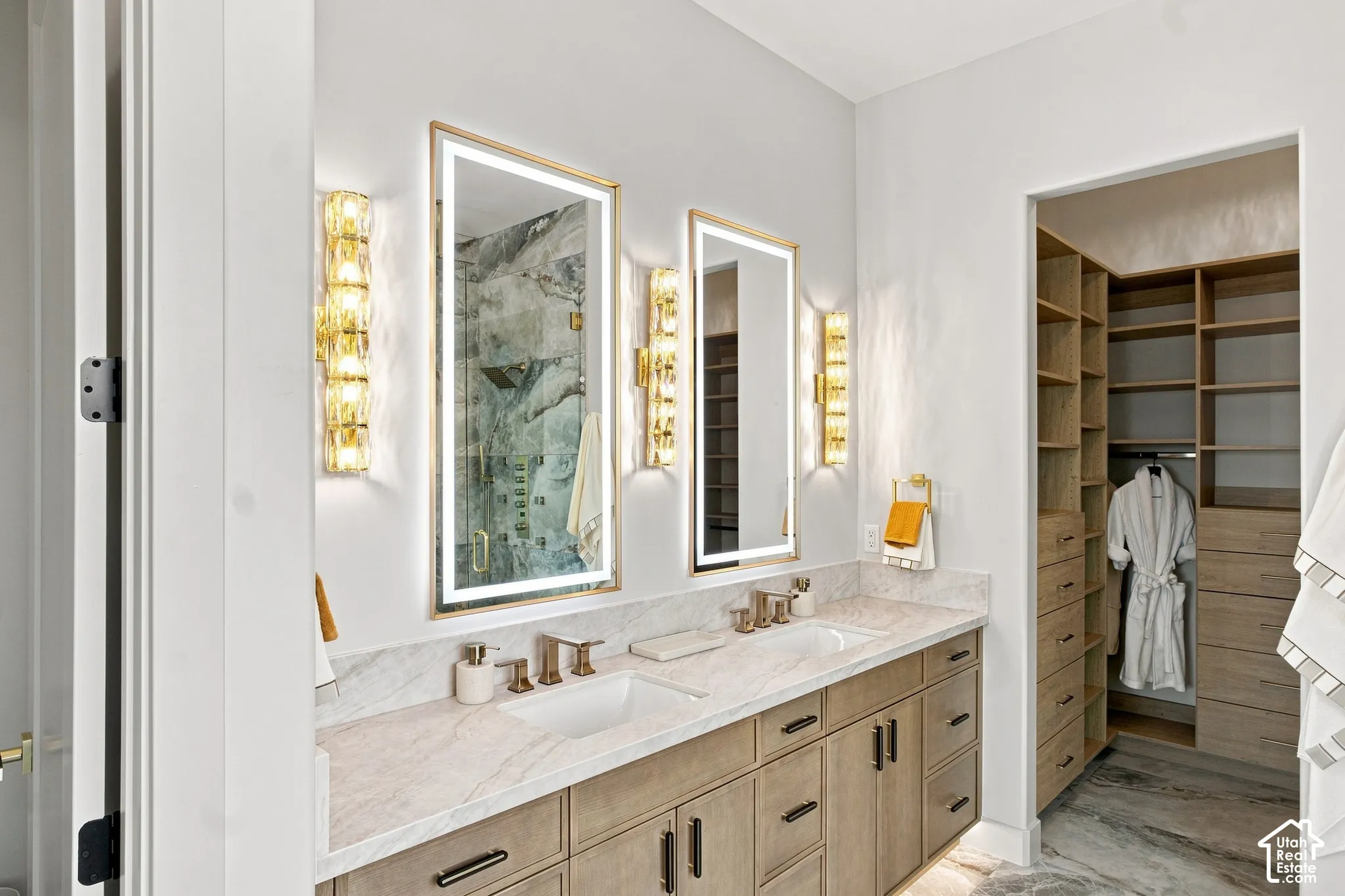 Dual vanity with stone countertop, undermount sinks, and wall-mounted light fixtures