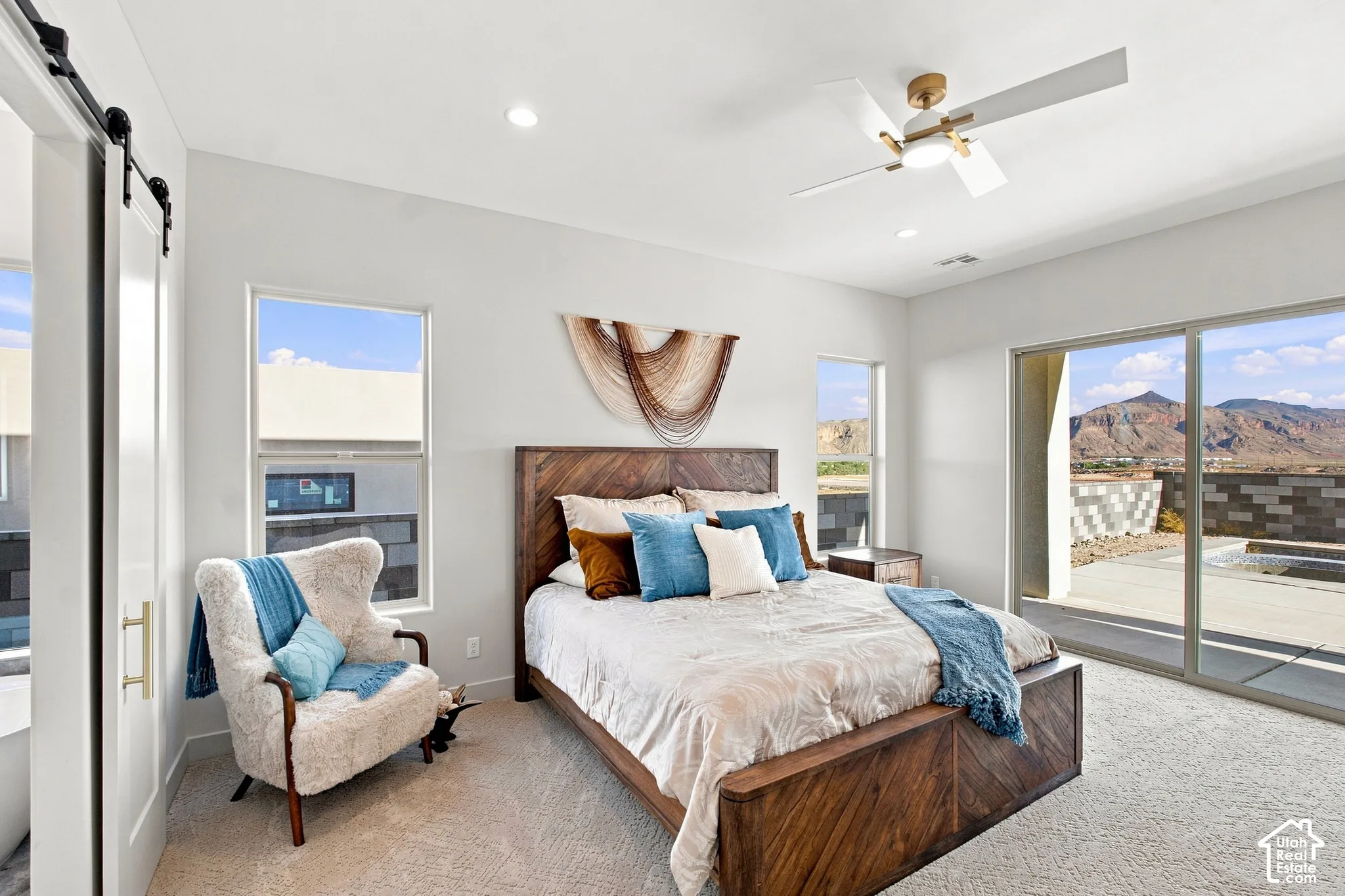Spacious bedroom featuring light-colored carpeting, a contemporary ceiling fan, recessed lighting, and a barn door