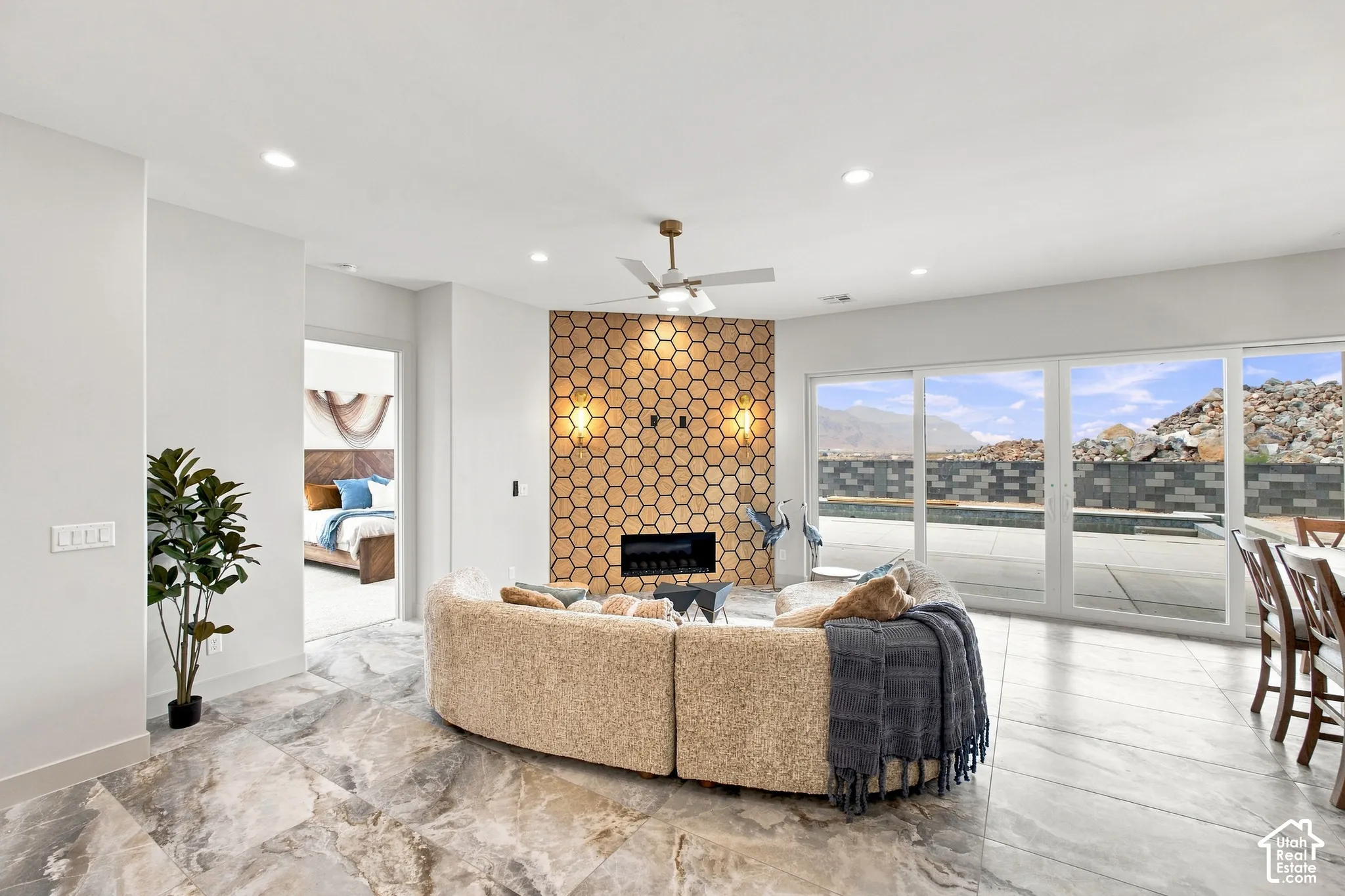 Polished tile flooring, a decorative hexagonal wall feature with sconces, an integrated fireplace, recessed lighting, and expansive sliding glass doors