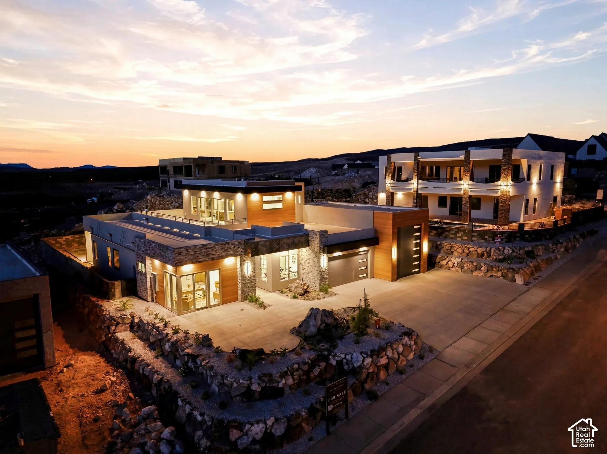 Contemporary exterior featuring multi-level architecture, stone facade accents, wood-finish paneling, an attached garage, and a concrete driveway