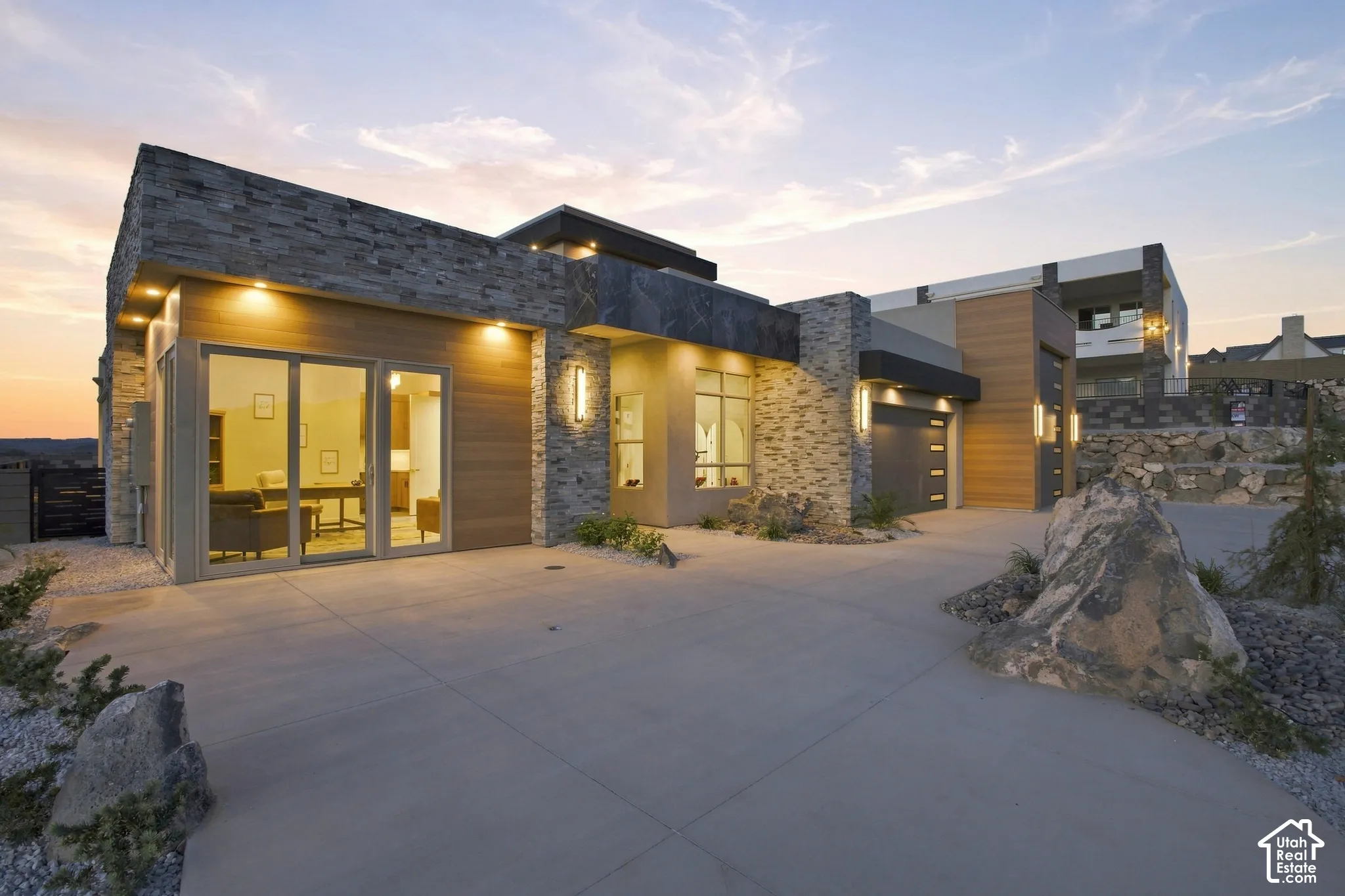 Contemporary exterior featuring stone cladding, wood-finish siding, a multi-pane sliding glass door, and a concrete driveway