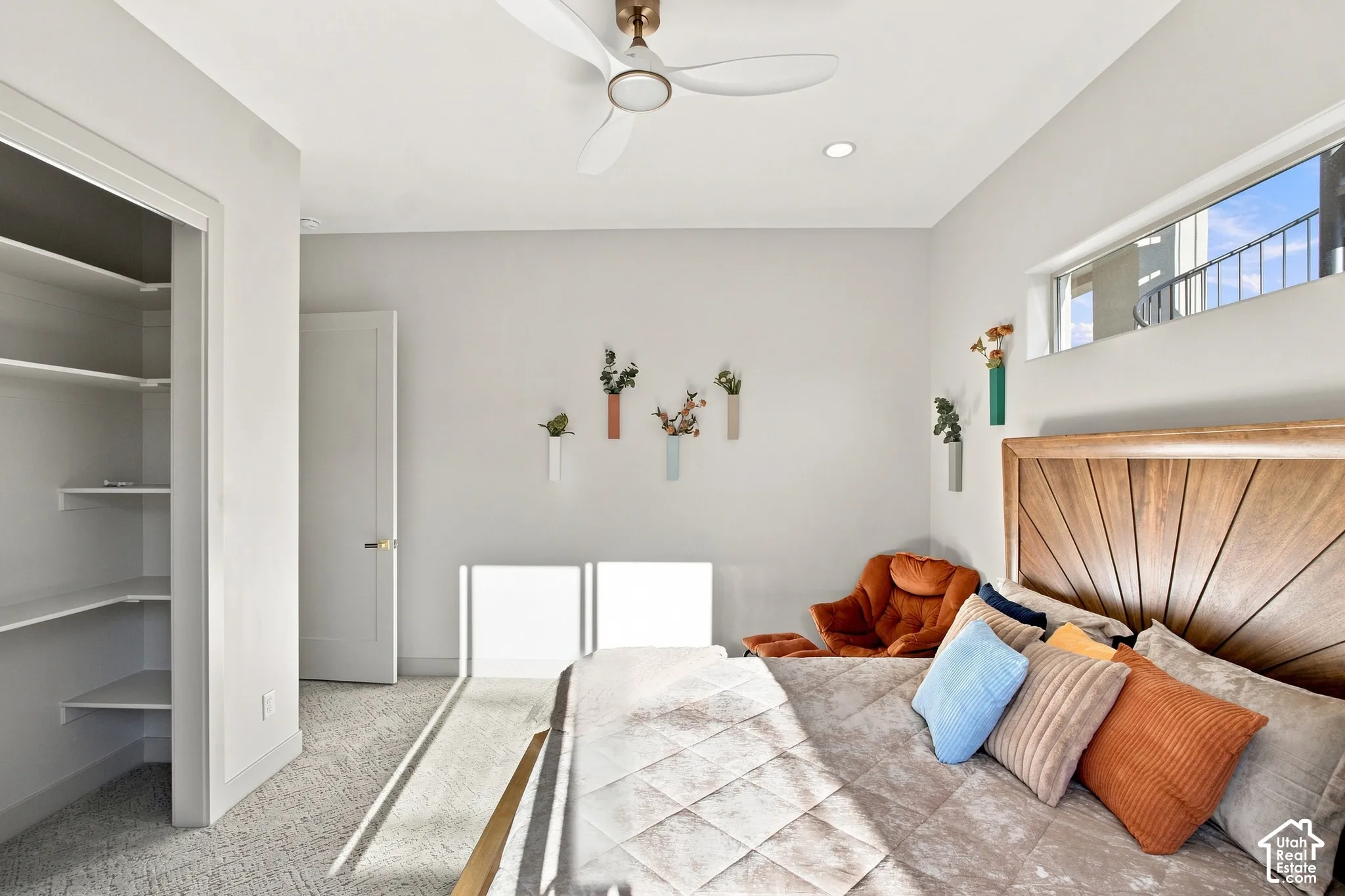 Recessed lighting, ceiling fan with integrated lighting, built-in open shelving, high transom window, and wood-finish headboard