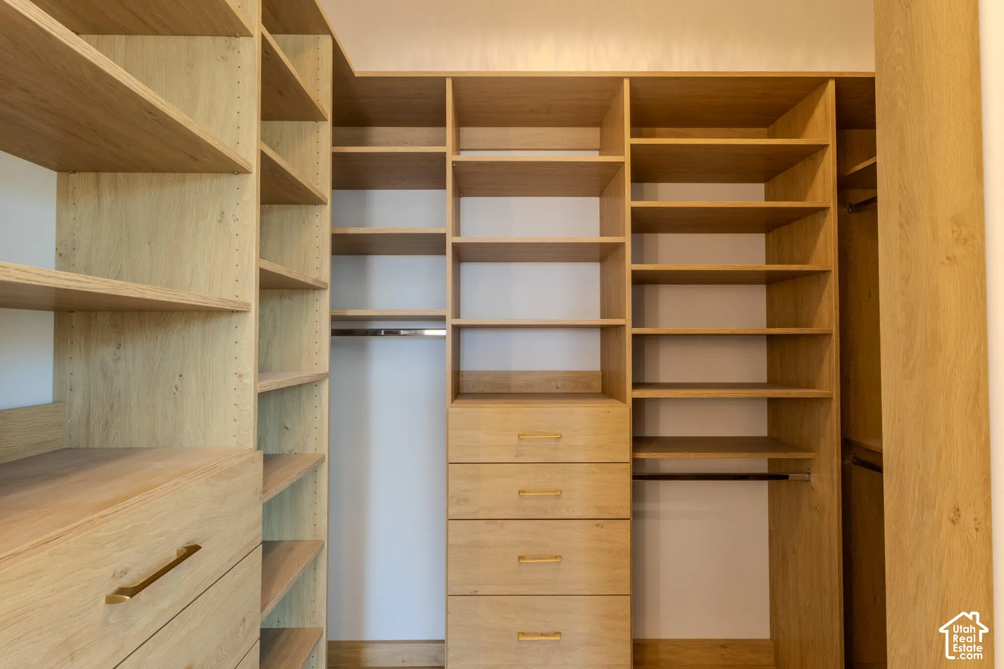 Custom closet system featuring light wood-finish shelving and drawers with gold-tone hardware