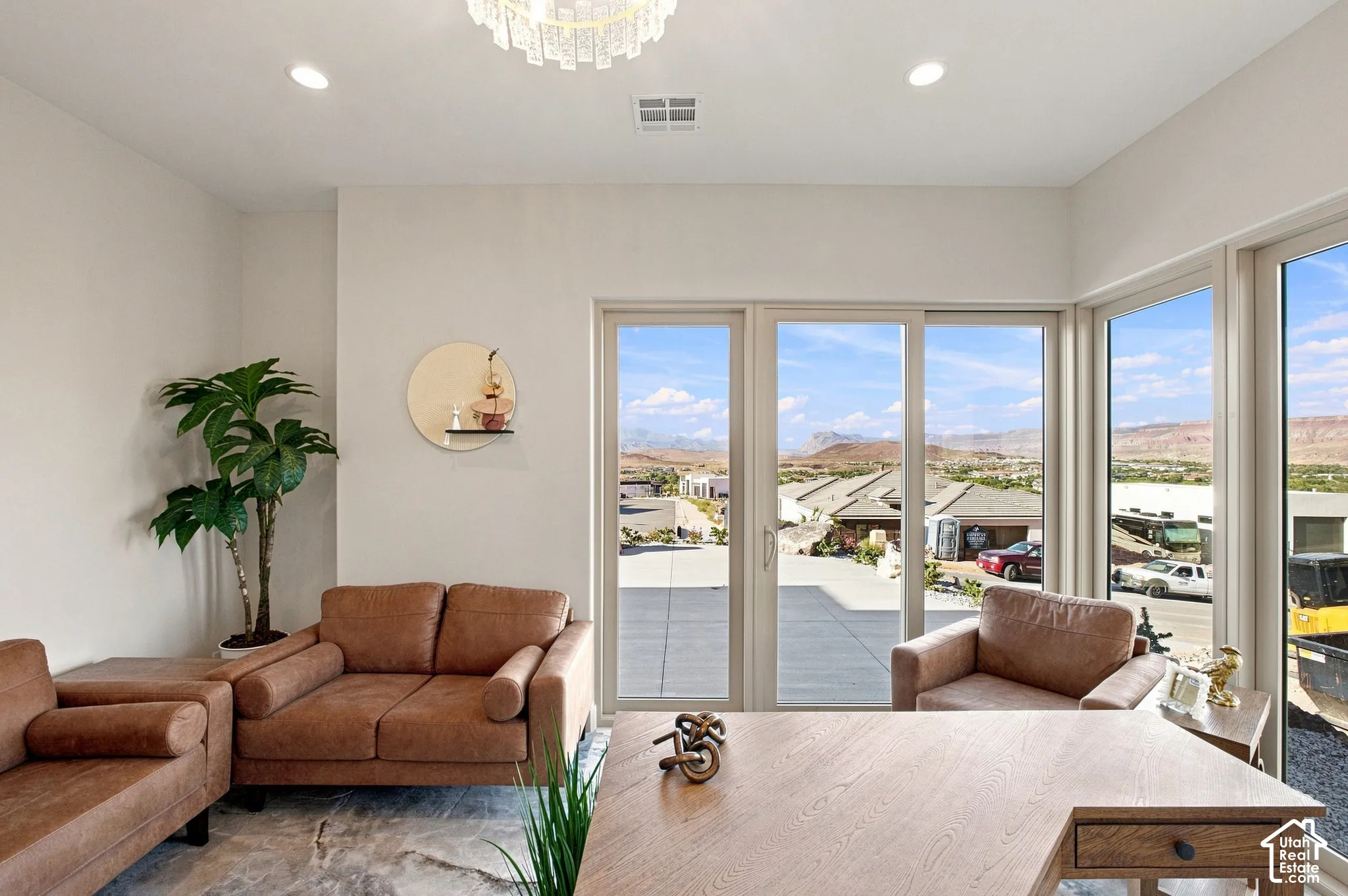 Expansive window wall with sliding glass door, recessed lighting, and a contemporary chandelier