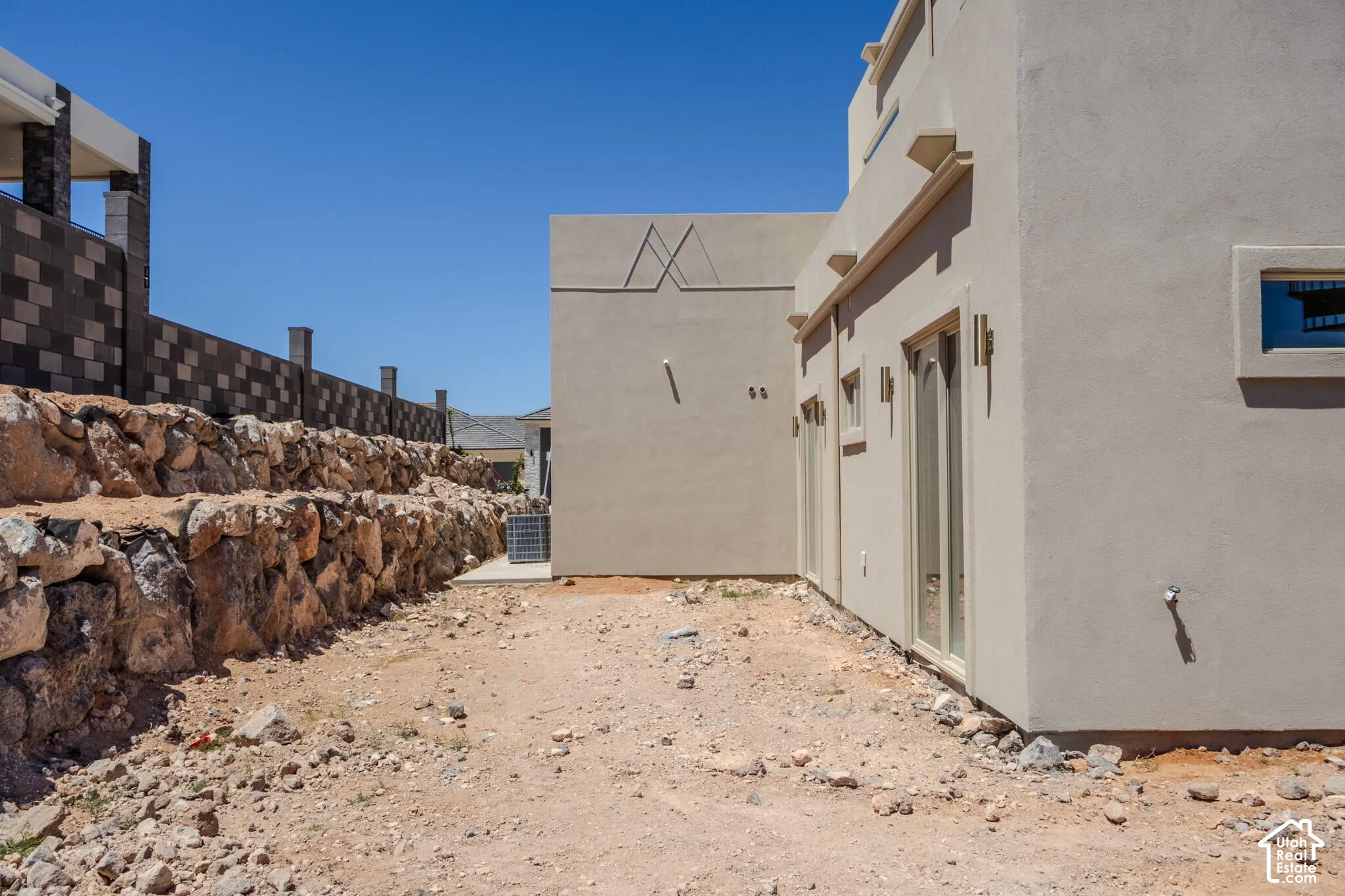 South-facing stucco exterior featuring multiple sliding glass doors and a square window