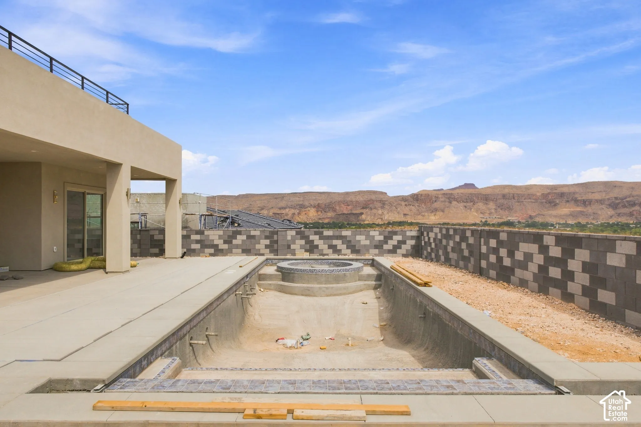 Pool area with a fire pit, concrete patio, and a retaining wall with a patterned finish