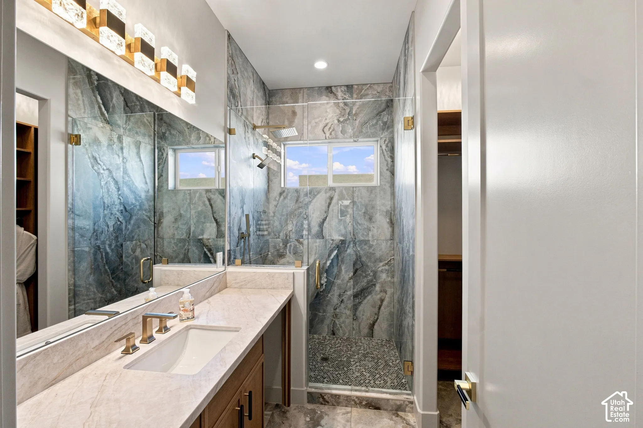 Walk-in shower with full-height stone-look tile and mosaic floor