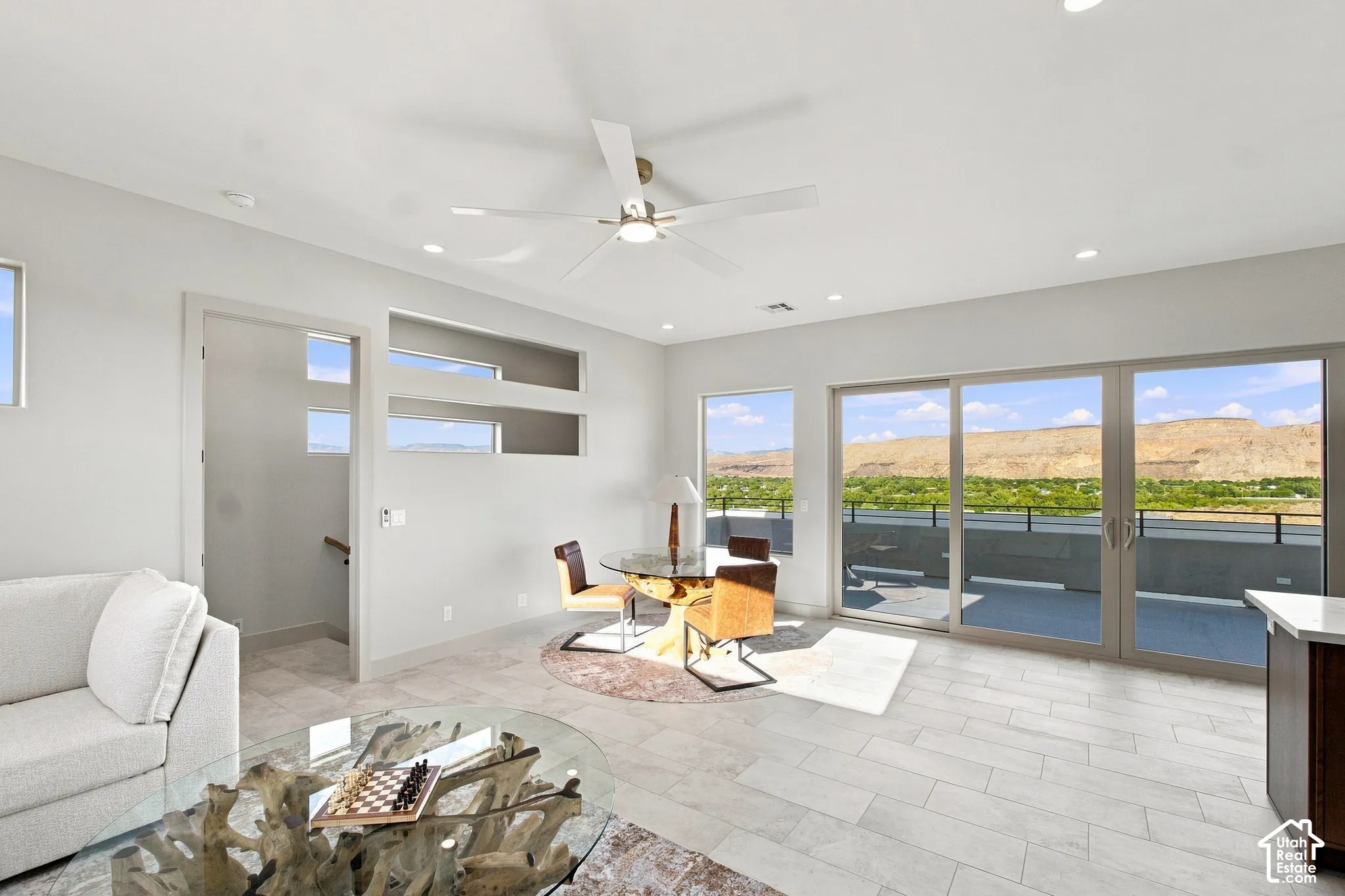 Bright living area with large sliding glass doors, white tile flooring, recessed lighting, ceiling fan, and decorative wall cutouts