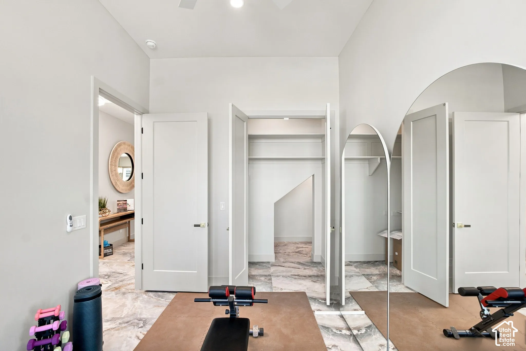 Interior room featuring light gray walls, white flat-panel doors, and a marble-look tile floor