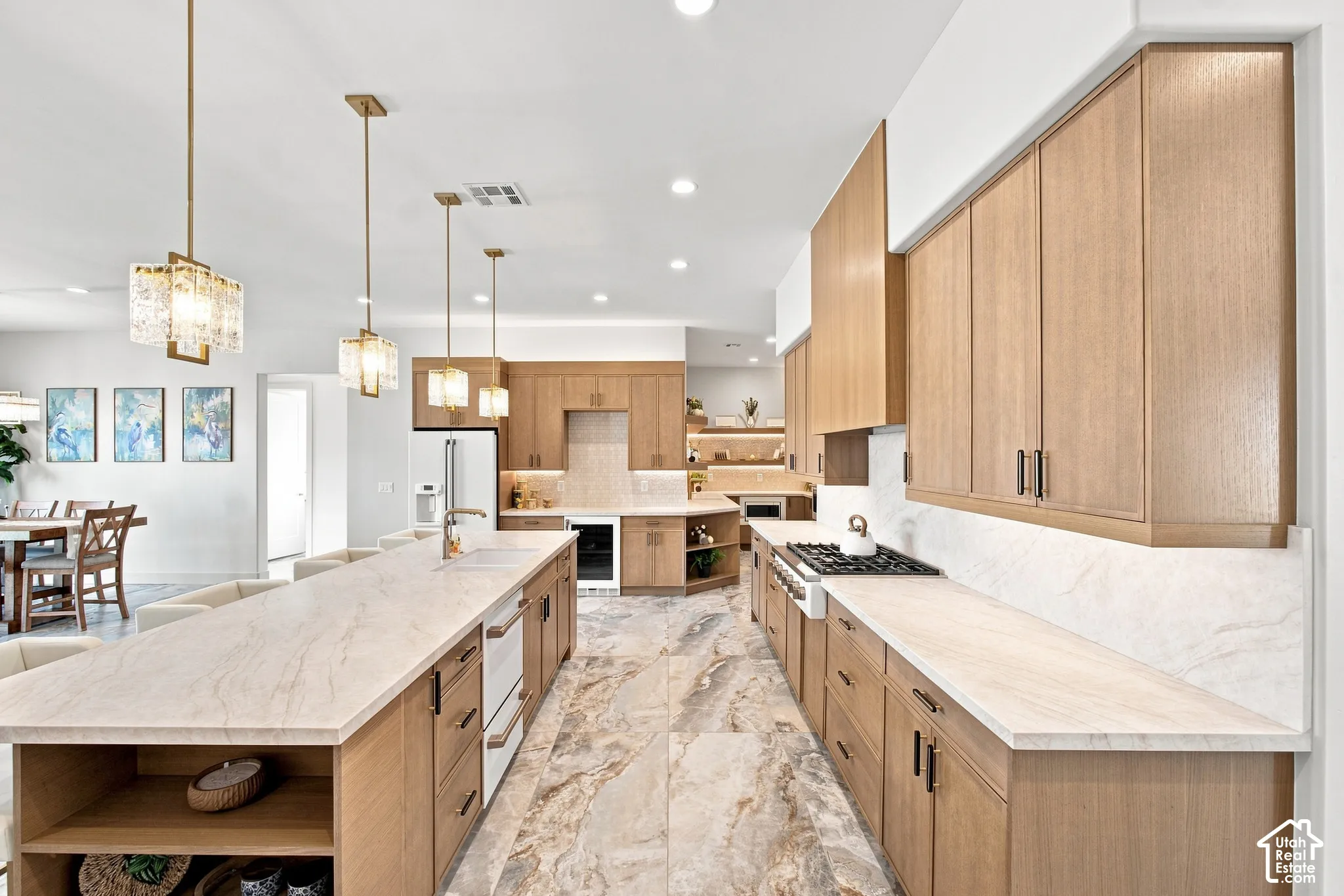 Gourmet kitchen featuring a large central island, light wood-finish cabinetry, integrated gas range, and extensive countertop space