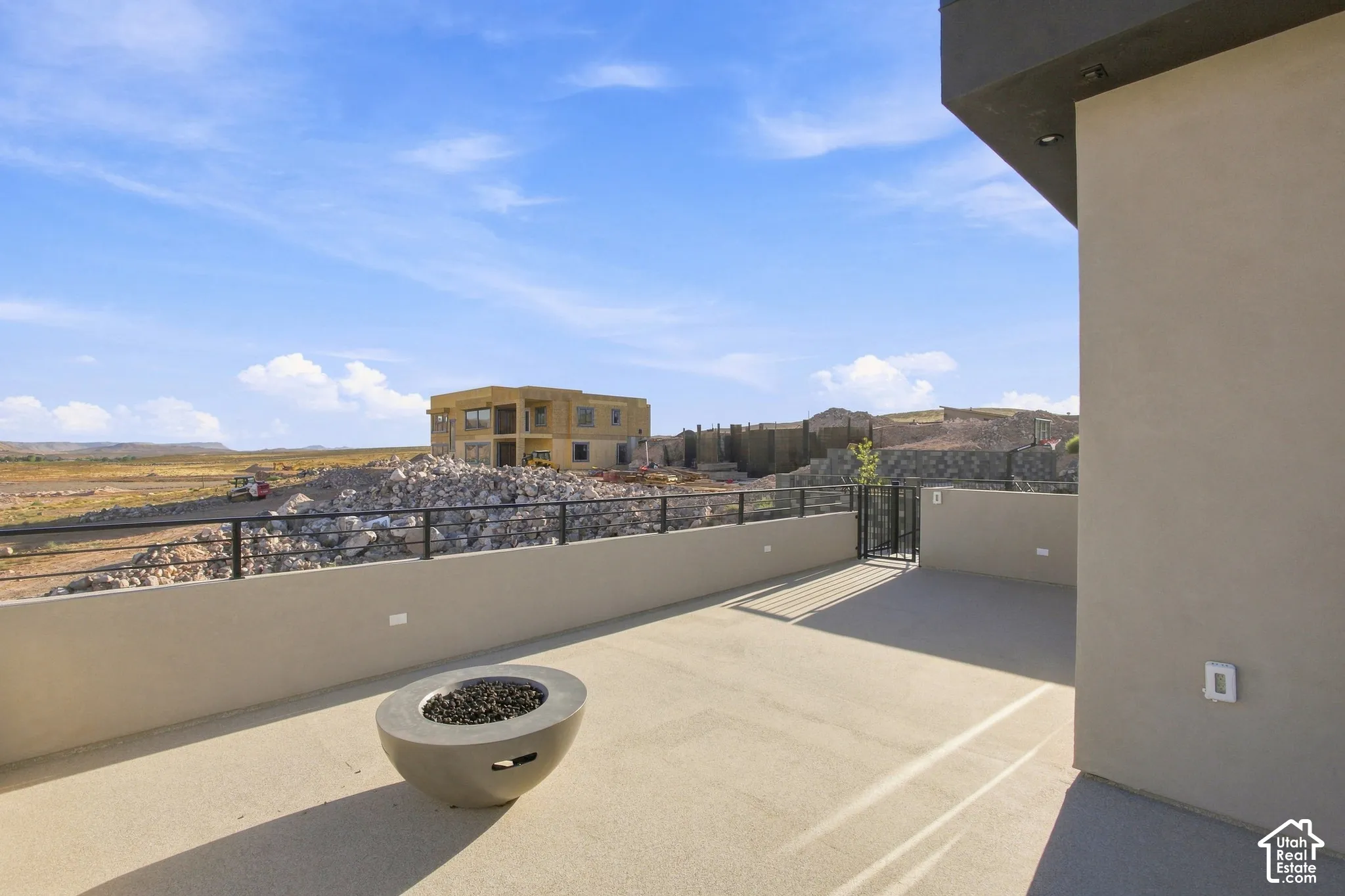 Expansive outdoor deck featuring a concrete fire pit, black metal railings, and a secure gate