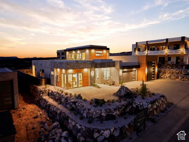 Contemporary exterior featuring stone accents, wood paneling, an attached garage, and a concrete driveway
