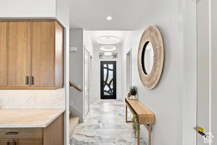 Hallway featuring stone-look flooring, recessed lighting, and a dark wood-finish entry door with frosted glass accents