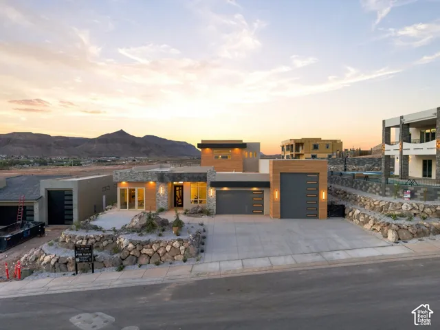 Modern exterior architecture featuring a multi-tone facade, integrated garage with a wood-finish door, and stone accents