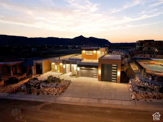 Contemporary architecture featuring a multi-level design, stone and wood-finish exterior accents, integrated garage, and a concrete driveway