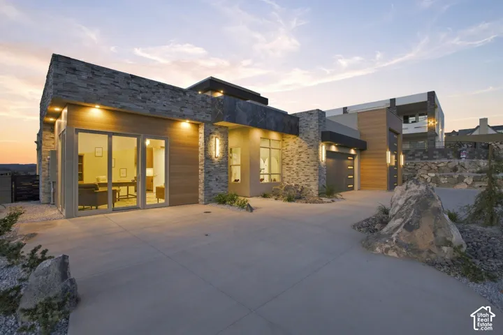 Contemporary exterior featuring stone cladding, wood-finish siding, a multi-pane sliding glass door, and a concrete driveway