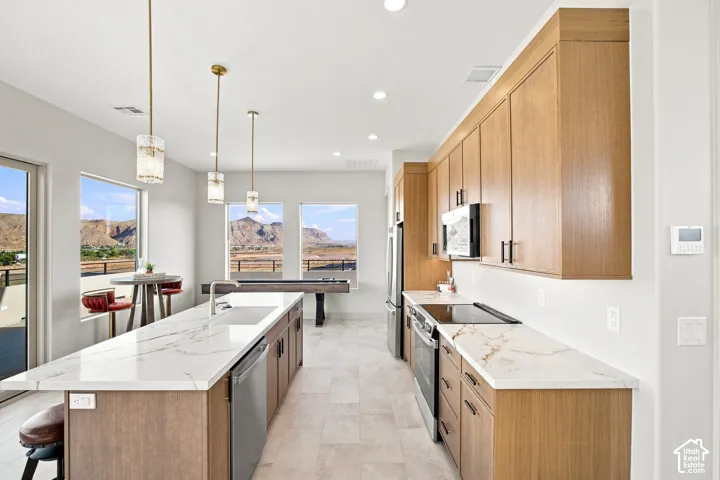 Open-concept kitchen with light wood-finish cabinetry, white countertops, stainless steel appliances, and recessed lighting