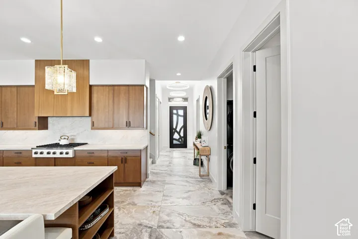 Kitchen featuring wood cabinetry, light-toned countertops, and a gas range