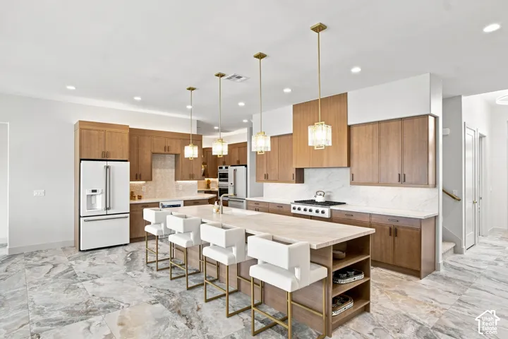 Open-concept kitchen with wood cabinetry, light-toned countertops, and a full suite of stainless steel appliances
