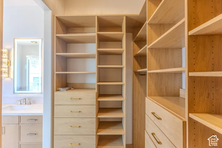 Custom closet system with integrated shelving and drawers, light wood-finish cabinetry, and gold-tone hardware