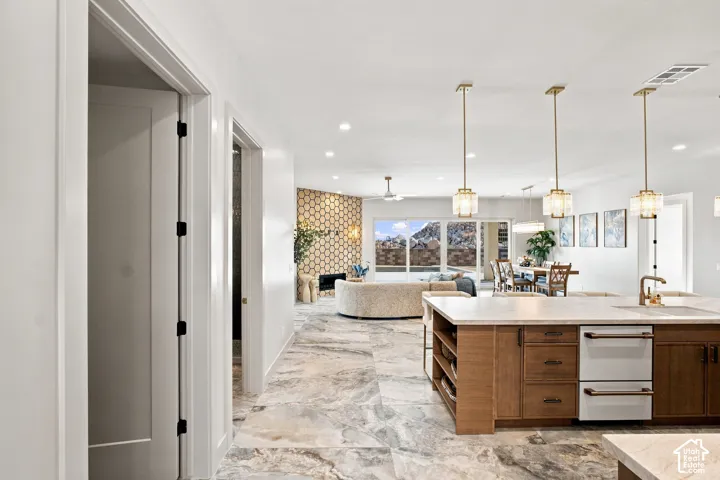 Open-concept kitchen with a large island, wood cabinetry, and integrated appliances
