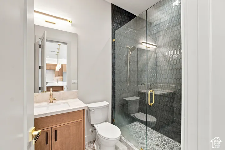 Glass-enclosed shower with dark hex tile and integrated bench