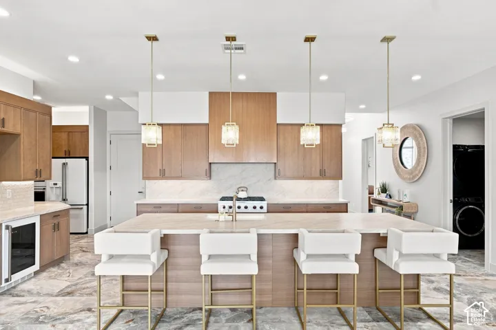 Kitchen featuring wood-finish cabinetry, a large center island with seating, a white tile backsplash, and recessed lighting