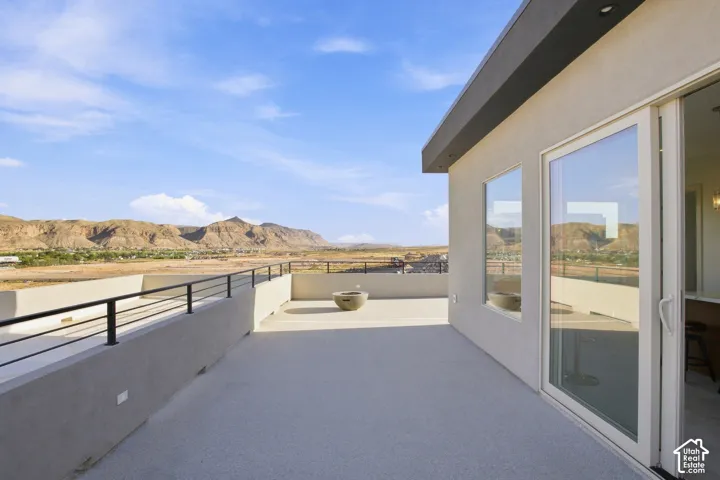 Expansive rooftop deck featuring a stucco exterior, black metal railings, and sliding glass doors